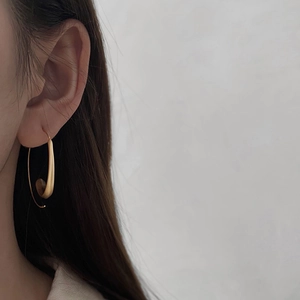 Close-up of matte gold irregular curved hoop earrings worn by a model for a chic look