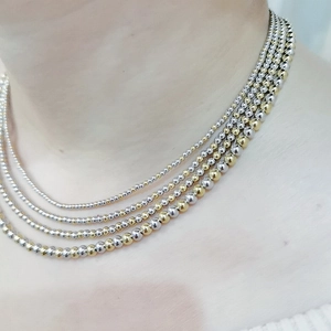 Detail of five-layer gold and silver stainless steel beaded necklaces worn on the neck