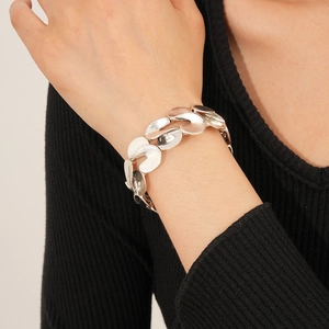 Close-up of a silver S-shaped interlocking metal bracelet worn on a woman's wrist