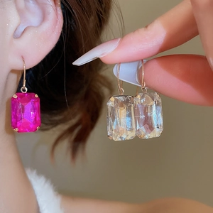 Close-up of elegant gold earrings with rose pink and clear square-cut crystals
