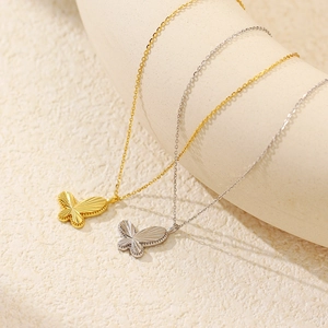 Close-up of gold and silver butterfly pendants with intricate floral textures
