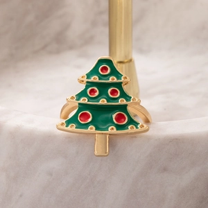 Close-up of green and red enamel Christmas tree ring with golden base on marble texture