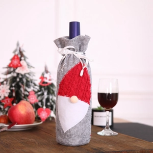 Detail of gray felt Christmas wine bottle cover with gnome embroidery on a festive table