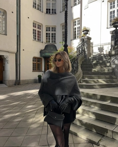 Detail of grey knitted poncho shawl paired with black leather gloves and a handbag