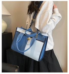 Detail of color-block denim tote bag with adjustable strap shown on a model
