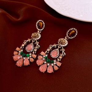 Detail of vintage drop earrings with colorful gemstones and rhinestones on red silk