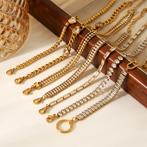 Detail of gold-plated bracelets featuring zircon stones draped over a wooden jewelry box