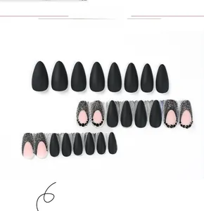Detail of matte black press-on nails with glitter french tips and rhinestone accents