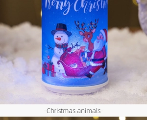 Close-up of blue Christmas LED candle featuring Santa, snowman, and reindeer on faux snow