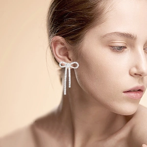 Sparkling silver bow knot earrings with long tassels on a model for elegant bridal style