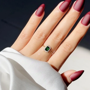 Detail of a square green emerald ring with diamond halo on a gold chain band