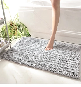 Close-up of foot on thick grey chenille bath mat next to bathtub for soft touch