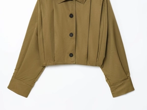 Detail of olive green cropped jacket featuring lapel collar and structured pleated fabric