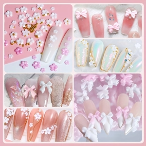 Collage of white and pink resin nail art charms with 3D bows and floral patterns