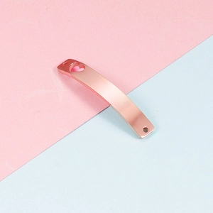 Detail van een gebogen roségouden metalen hanger met hartvormig gat en dubbele gaten