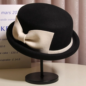 Detail view of a vintage wool felt bowler hat with a large elegant cream bow accent