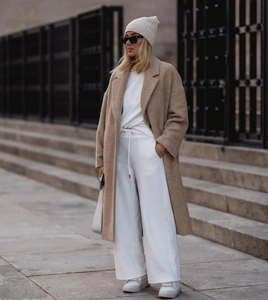 Vue complète d'un long manteau en laine beige avec un ensemble de loisirs blanc chic