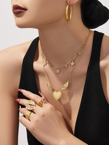 Detail shot of a dual-layer gold heart necklace and matching earrings worn by a model