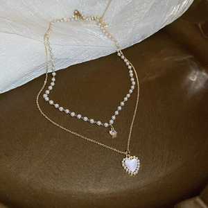 Detail of double-layer necklace featuring heart shell pendant and pearl zircon strands