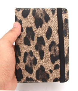Detail showing leopard print passport holder with faux leather texture and elastic band