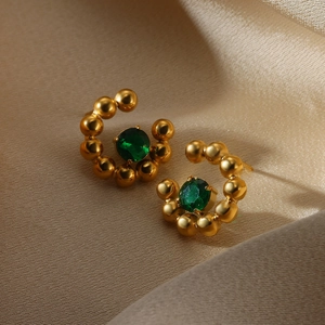 Detail of C-shaped gold-plated stainless steel earrings with green crystal and gold beads