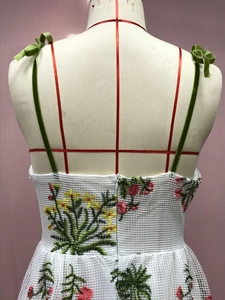 Detail der bunten Blumenstickerei und grünen Samtträger am weißen Netzkleid