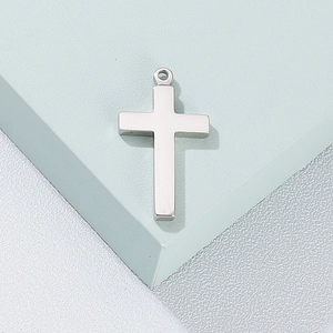 Pendentif croix en acier inoxydable argenté poli sur un fond bicolore minimaliste