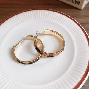 Macro view of gold hoop earrings featuring leopard print leather texture on a white plate