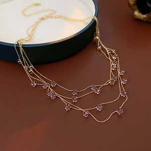Gros plan du collier doré multicouche avec pendentifs ronds élégants en zircon violet