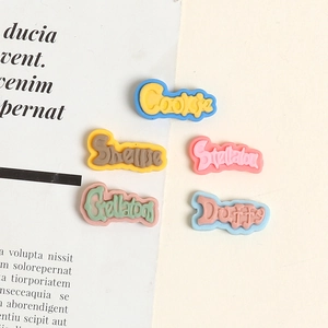 Macro detail of colorful resin letter charms featuring character names for DIY crafts