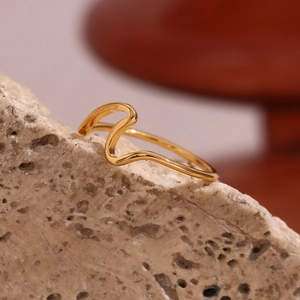 Macro detail of 18K gold plated minimalist wave ring on textured stone background