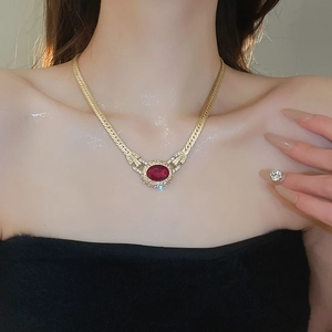 Close-up of vintage gold snake chain necklace with large oval red gemstone and diamonds