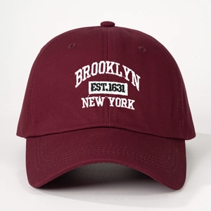 Close-up of white Brooklyn New York embroidery on wine red cotton baseball cap