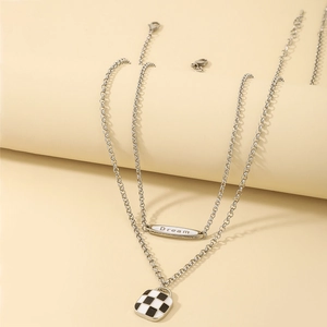 Close-up of double layer silver necklace with Dream tag and checkerboard square pendant