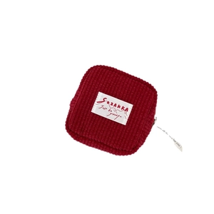 Red corduroy mini pouch with white label and zipper detail for coins and cards