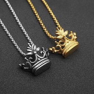 Detail shot of silver and gold crown pendants on box chains with metallic luster