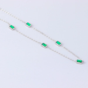 Macro shot of silver stainless steel necklace featuring five rectangular green zircons