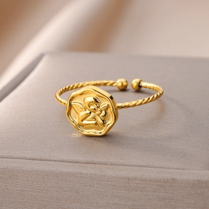 Macro view of gold-plated twisted ring band with embossed angel coin detail