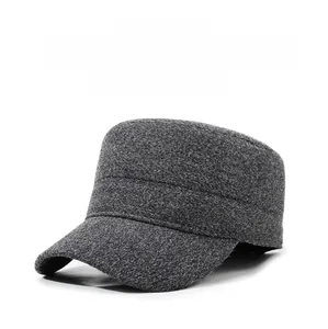 Detail of dark gray wool flat top winter hat with ear flaps and metal letter logo