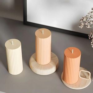 Minimalist striped cylindrical pillar candles in warm tones on a wooden tray decor