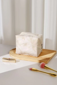 Vue détaillée de la trousse à maquillage en lin crème avec broderie florale en 3D