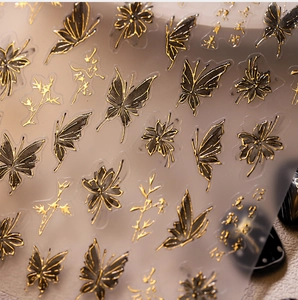 Détail macro de stickers ongles 3D avec papillons noir et or et calligraphie chinoise