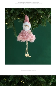 Pink plush angel doll with golden heart hanging on a Christmas tree branch