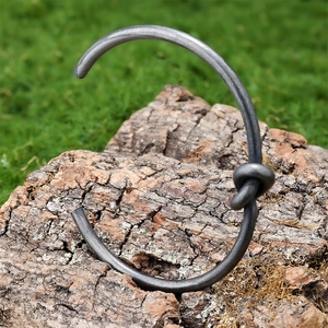 Vintage stainless steel open bangle with knot design on natural bark background