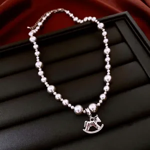 Luxurious grey pearl necklace with silver rocking horse pendant on black leather tray