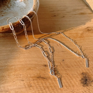 Minimalist S925 sterling silver chain necklaces on a rustic wooden surface with natural light