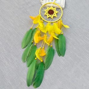 Handcrafted sunflower dreamcatcher with yellow feathers and beads on gray background