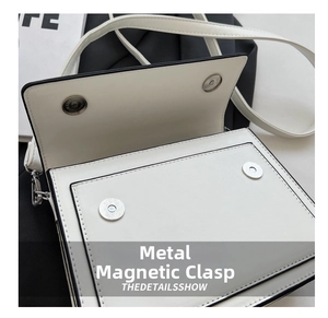 Detail shot of the dual metal magnetic snap closures on the white square crossbody bag