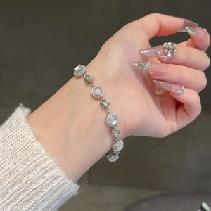 Detail of silver bracelet with zircon stone inlay and star charms on model wrist