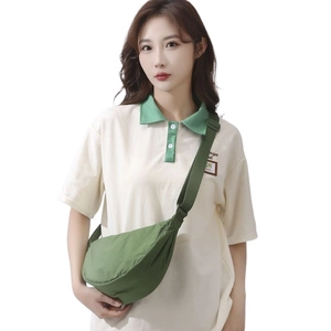 Minimalist green nylon crossbody half-moon bag worn by model on a plain background
